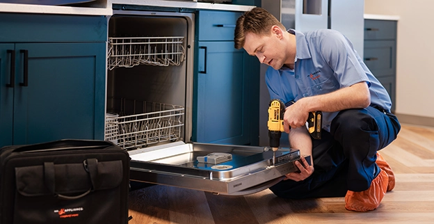 Technician repairing a dishwasher in a home kitchen